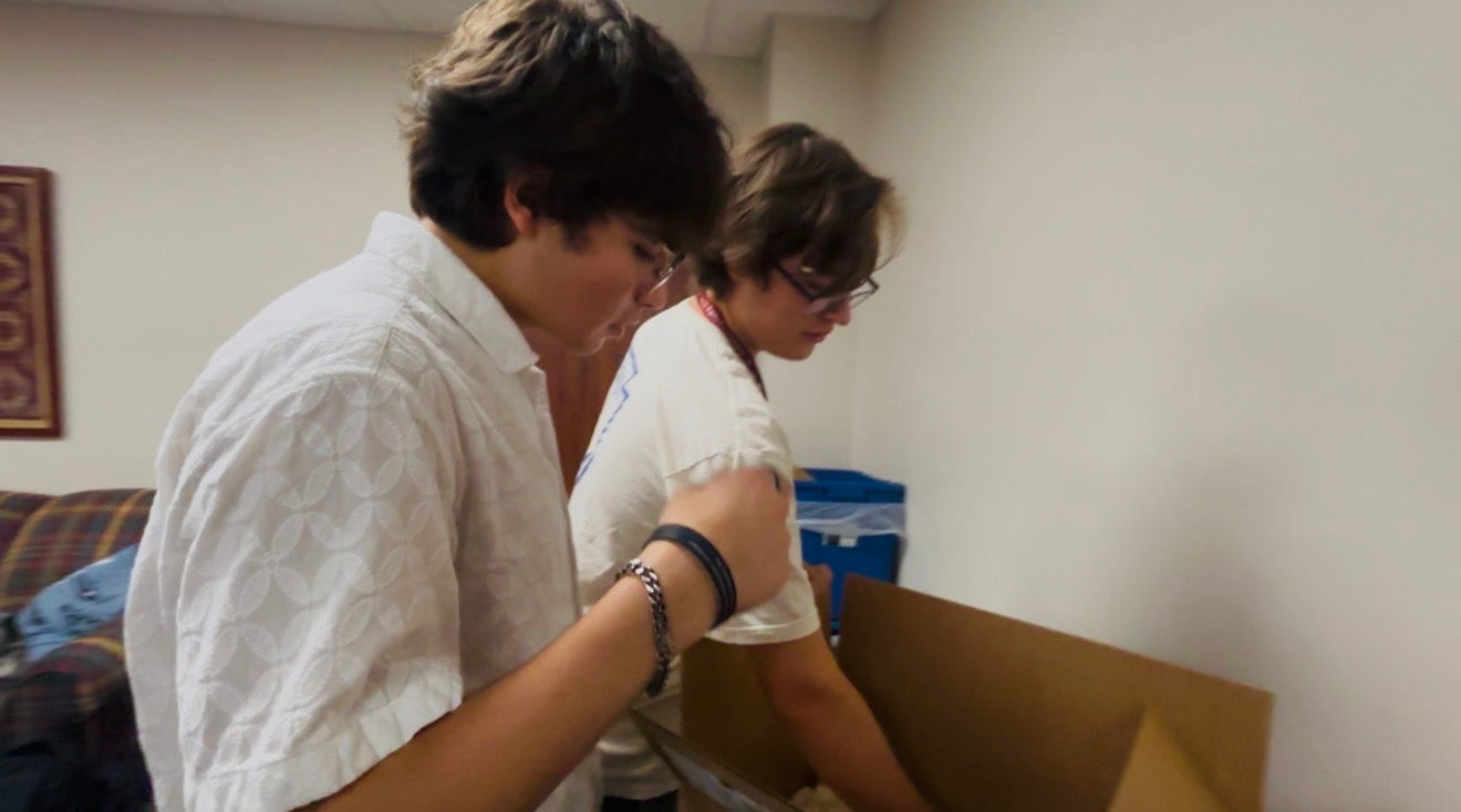 Two team members opening a box of supplies